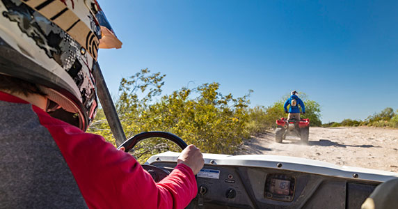 Person riding a dune buggy on the beach wearing a helmet